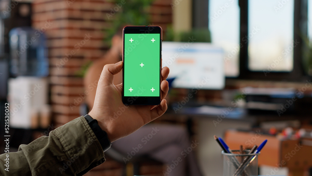 Poster businessman analyzing smartphone with greenscreen display in startup office. looking at isolated cop