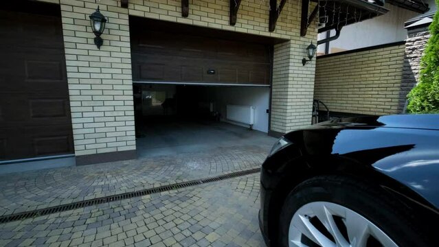 Man driver in car thumbed remote control to open the garage door in the house