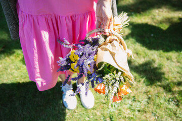 summer bouquet of yellow yarrow and lavender bouquet in woman's hands shot from above, woman wearing a pink dress - 521532015