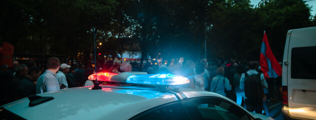Group of protesting young people and police car