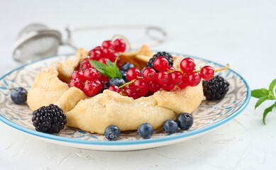 Fruit tart with red currants sprinkled with powdered sugar on a white table