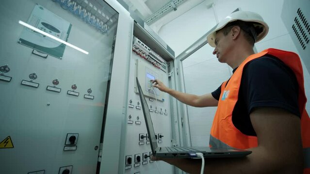 Electrical engineer working check the electric current voltage and overload at front of load center cabinet or consumer unit for maintenance in main power distribution system room.