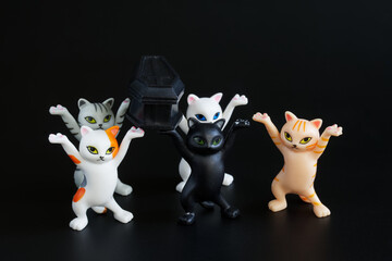 Funny toy dancing kittens from the meme carry a black coffin. Concept of a funeral procession...