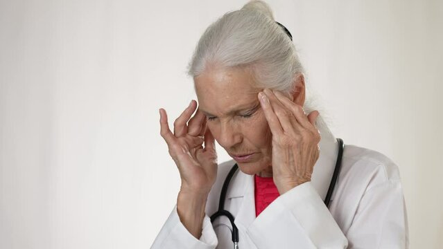 Profile of exhausted woman doctor rubbing forehead and look at camera, tired girl doctor feels headache from working hard.