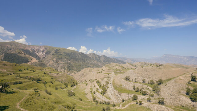 Aerial view of amazing landscape with beautiful valley on a sunny day. Action. Flying above summer mountains on blue cloudy sky background.