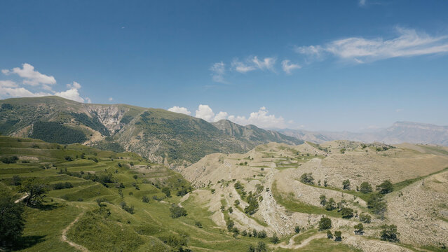 Aerial view of amazing landscape with beautiful valley on a sunny day. Action. Flying above summer mountains on blue cloudy sky background.