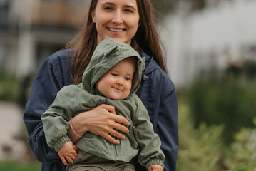 A happy mother is holding her young daughter on a cloudy day.