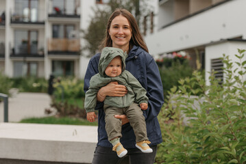 A happy mother is holding her young daughter on a cloudy day.