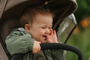 A female toddler is sitting in the stroller on a cloudy day.