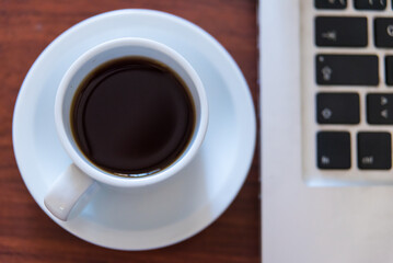 coffee cup on wooden table, laptop next to you