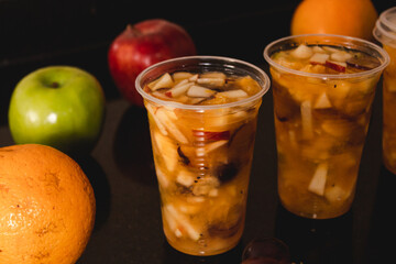 Juice with fruit salad around fruit on a black table.