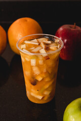 A juice with fruit salad on top of a black table.