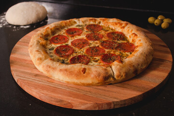 Pepperoni pizza with stuffed rim on top of a black table.
