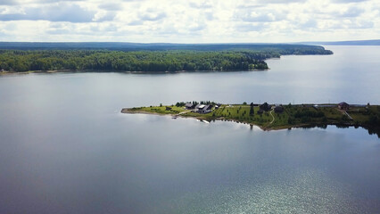 The view from the drone. Clip. a huge clear lake in the background is a large green forest and a calm sky.