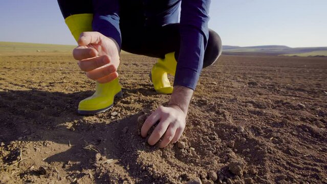 Grabs and pours the soil with the farmer's hand.
Farmer scooping soil in farmland. He takes the soil and pours it down from his palm.
