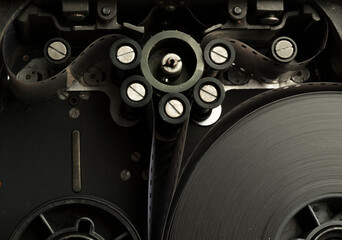 a roll of film in a film camera cassette. negative film in the tape drive mechanism of the cassette. show business film production technology concept