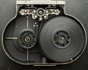 a roll of film in a film camera cassette. negative film in the tape drive mechanism of the cassette. show business film production technology concept