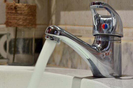 Chorro de agua cayendo de un grifo de un lavabo