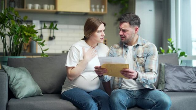 Upset Worried couple, man and pregnant woman at home, open envelope received a letter read with bad news, notice from bank reading loan denied worry with analysis results statement approval