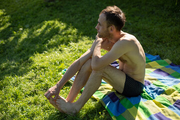 Guy is alone on beach. Man in shorts. Guy sunbathes in sun.