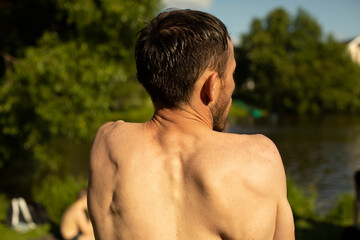 Guy's back in summer. Man's bare back on hot day. Middle-aged man on beach.