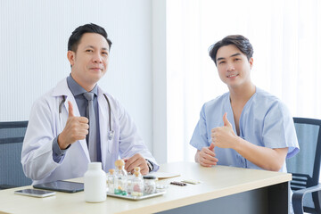 Male doctor and young male patient while consult and .explain. Doctor and patient sitting together at table in clinic