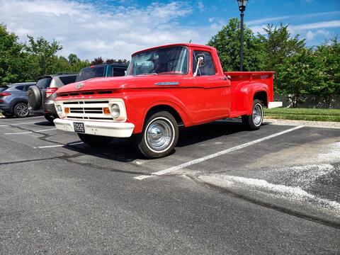 red classic 1955 Ford F-100 Pickup Truck. Parked in a parking lot next to an apartment building.