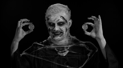 Zombie man with make-up with fake wounds scars showing golden bitcoins. Achievement career wealth, cryptocurrency investment, mining btc, future technology. Sinister dead guy. Halloween, filming