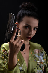 Portrait of independence strong woman holding revolver close to face. Concept Girl in style mafia...