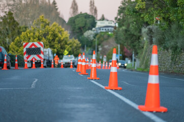 Road cones reduce street lanes while workers trim edge