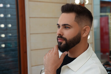 Young man with fresh haircut and groomed beard in barbershop - obrazy, fototapety, plakaty