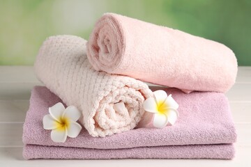 Obraz na płótnie Canvas Closeup view of soft folded towels and plumeria flowers on white wooden table