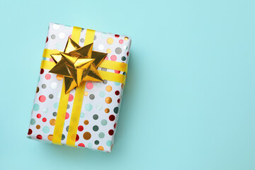 Beautifully wrapped gift box on turquoise background, top view. Space for text