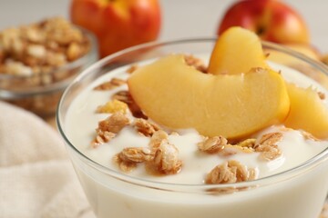 Naklejka na ściany i meble Tasty peach yogurt with granola and pieces of fruit in dessert bowl on table, closeup
