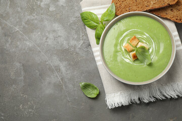 Tasty homemade zucchini cream soup served on grey table, flat lay. Space for text