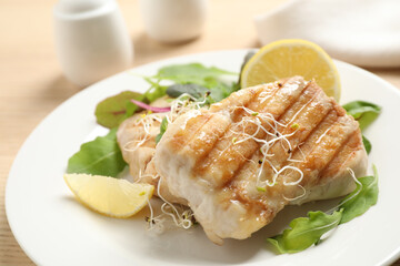Tasty grilled fish with lemon served on table, closeup
