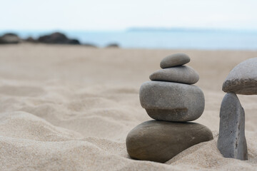 Fototapeta na wymiar Stacks of stones on beautiful sandy beach near sea, space for text