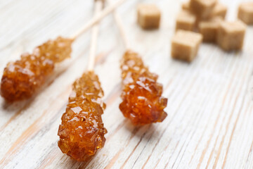 Sticks with sugar crystals on white wooden table, closeup. Tasty rock candies
