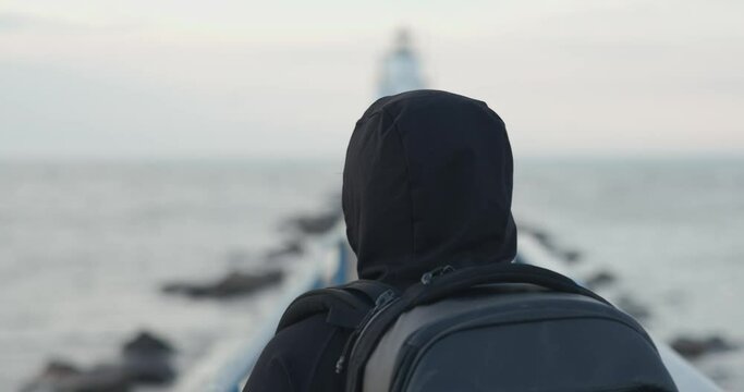 Head view slow motion of man walking to lighthouse.
