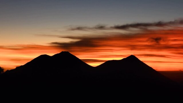 Siluetas de volcanes en el amanecer ilustrando uno de los destinos tur&iacute;sticos de Guatemala y c&oacute;mo el tiempo pasa muy r&aacute;pido cuando sale el sol