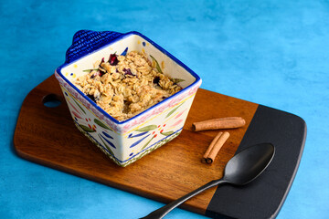 Fresh out of the oven blueberry crumble, in a single serving bowl with fresh cinnamon, on a medium blue background
