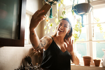 Talking on phone video call, waving and greeting while communicating, chatting and networking during lockdown. Smiling, happy and cheerful woman or vlogger using hand gesture and filming vlog at home