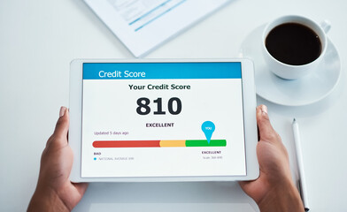 Good and positive credit score on the screen of a tablet from above. Applying for finance, a loan or a home mortgage bond online. Closeup of hands holding a wireless device while banking on the web