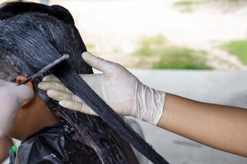 Hair color change with long hair dye chemicals by beautician.