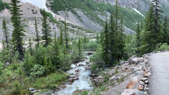 A small, fast-flowing stream set against a majestic mountain backdrop. Small, rapidly-moving stream in the mountains.