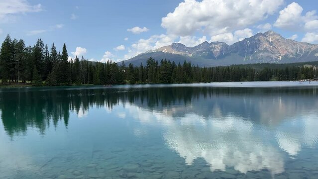 View of Beauvert Lake at Jasper, Alberta,Canada in a summer. The pristine alpine lake is surrounded by forest with mountain peaks in the distance. 