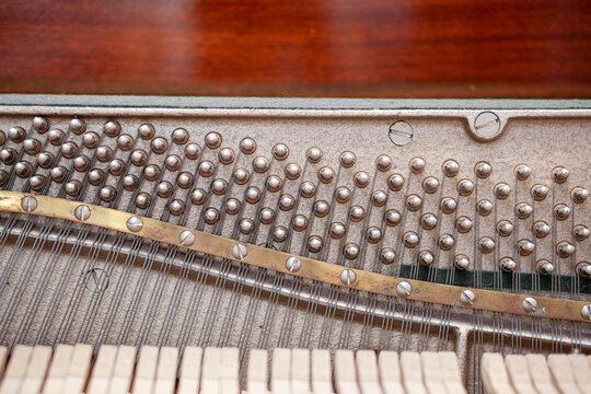 The inside of the piano is without a lid. Strings, hammers and other parts of a musical instrument are visible. Tuning and repair of a musical instrument