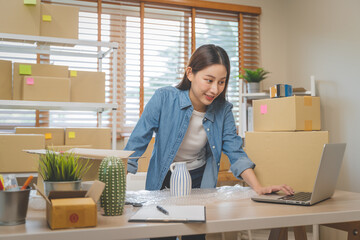 Young Asian woman owner of small online store packing customer orders in the home office.