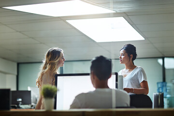 Young colleagues having a serious discussion at work in a modern office. Business women talking...