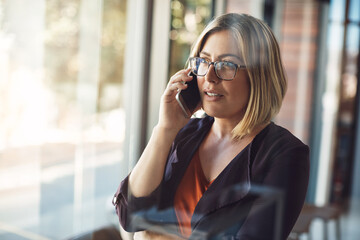 Businesswoman making a mobile phone call to have conversation with management about the company in a modern office. Confident professional blonde female in leadership talking on her smartphone - Powered by Adobe